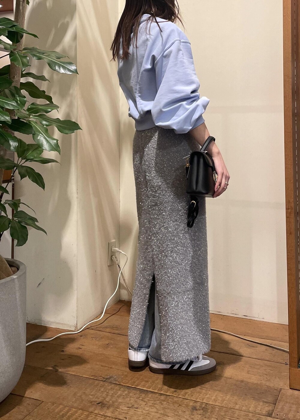 グレー系のスカート、ブルー系のデニムパンツ、ブラック系のショルダーバッグを着用したレディースの冬コーディネートの4枚目の写真