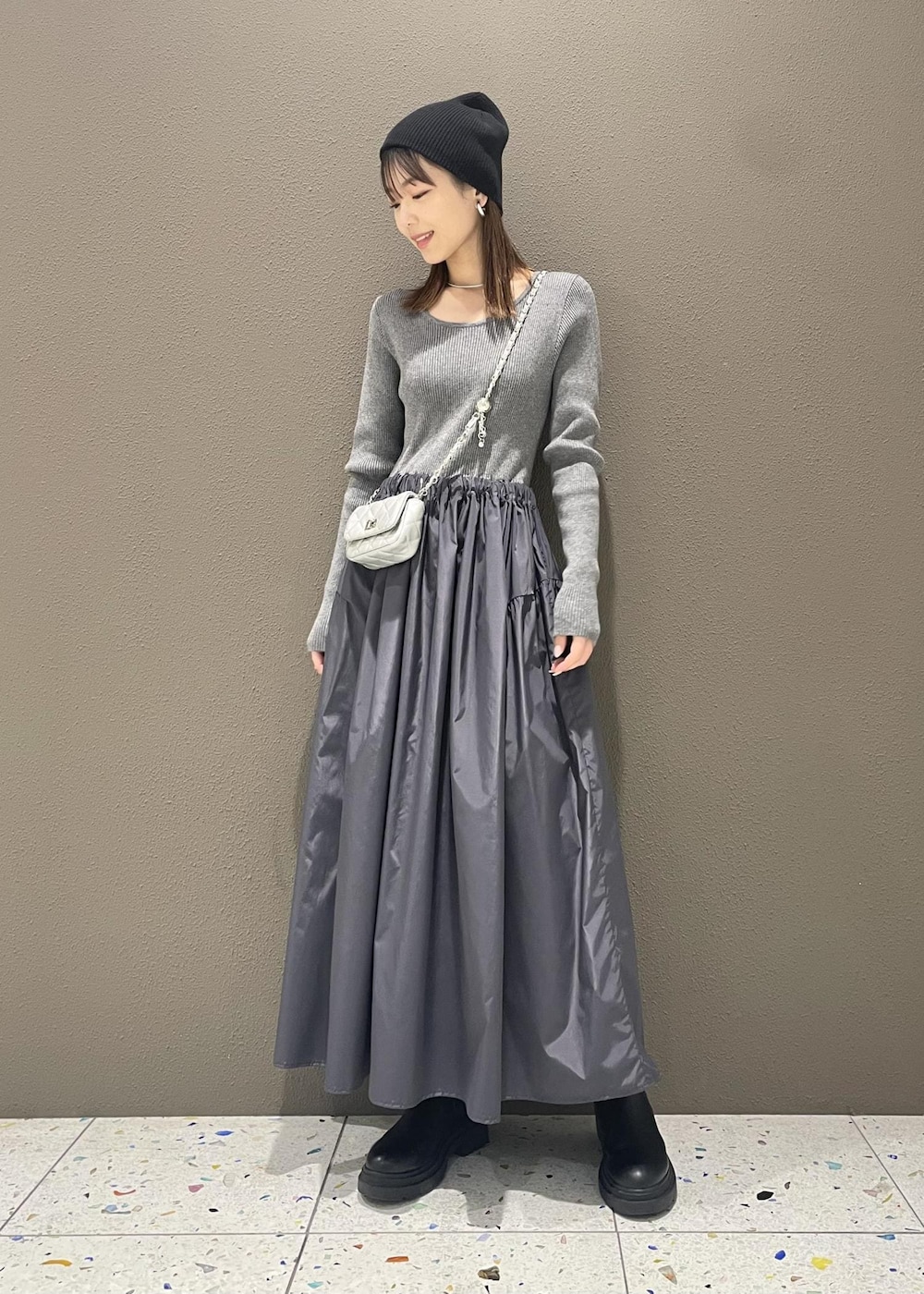 シルバー系のショルダーバッグ、グレー系のワンピースを着用したレディースの冬コーディネートの2枚目の写真