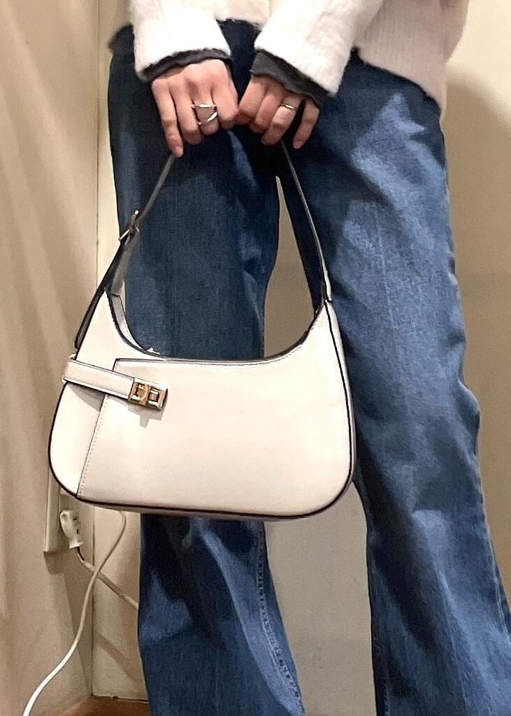 ブルー系のデニムパンツ、ブラック系のブーツ、ホワイト系のハンドバッグを着用したレディースの冬コーディネートの6枚目の写真