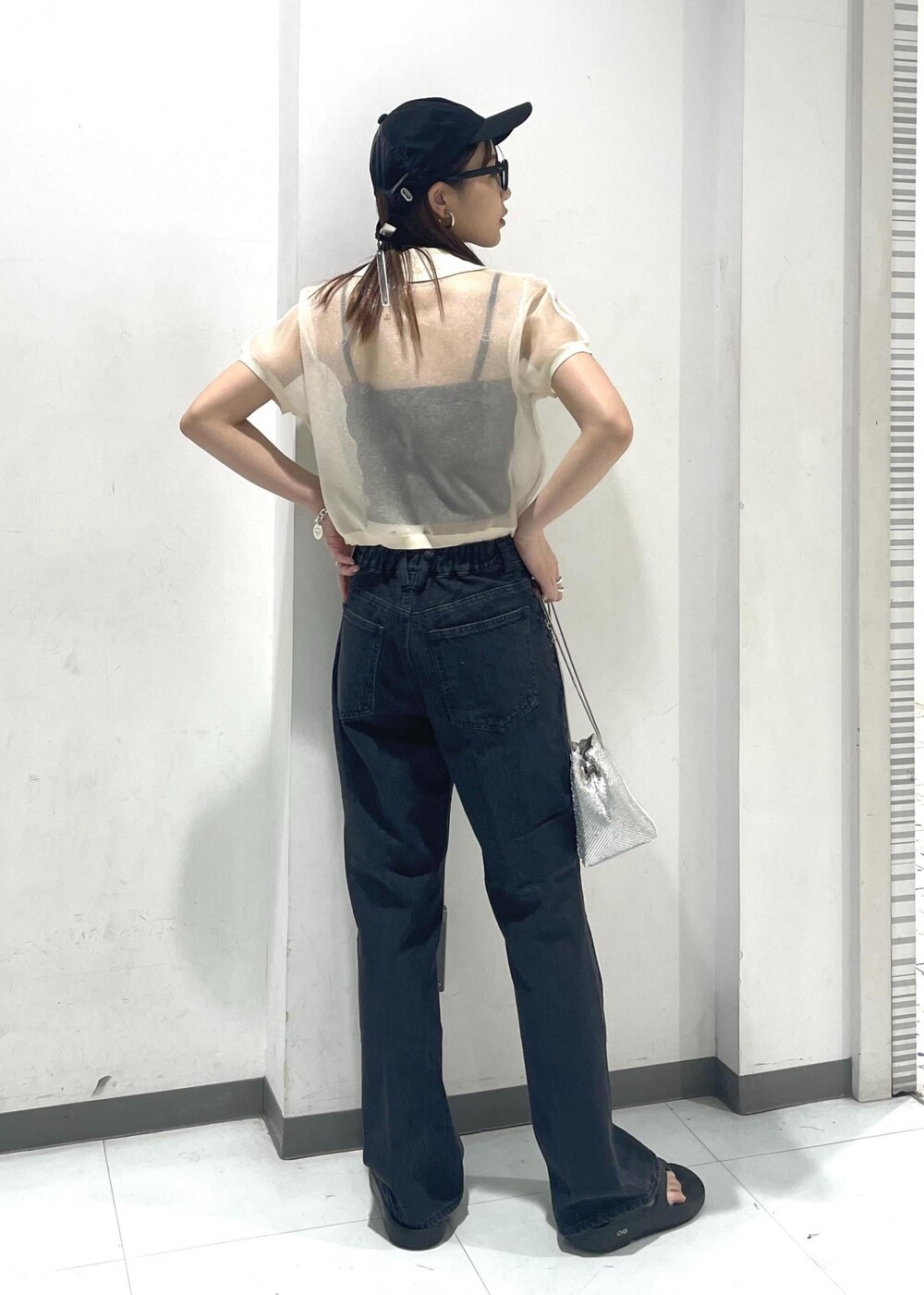 シルバー系のショルダーバッグ、ブラック系のデニムパンツ、ホワイト系のポロシャツを着用したレディースの夏コーディネートの3枚目の写真