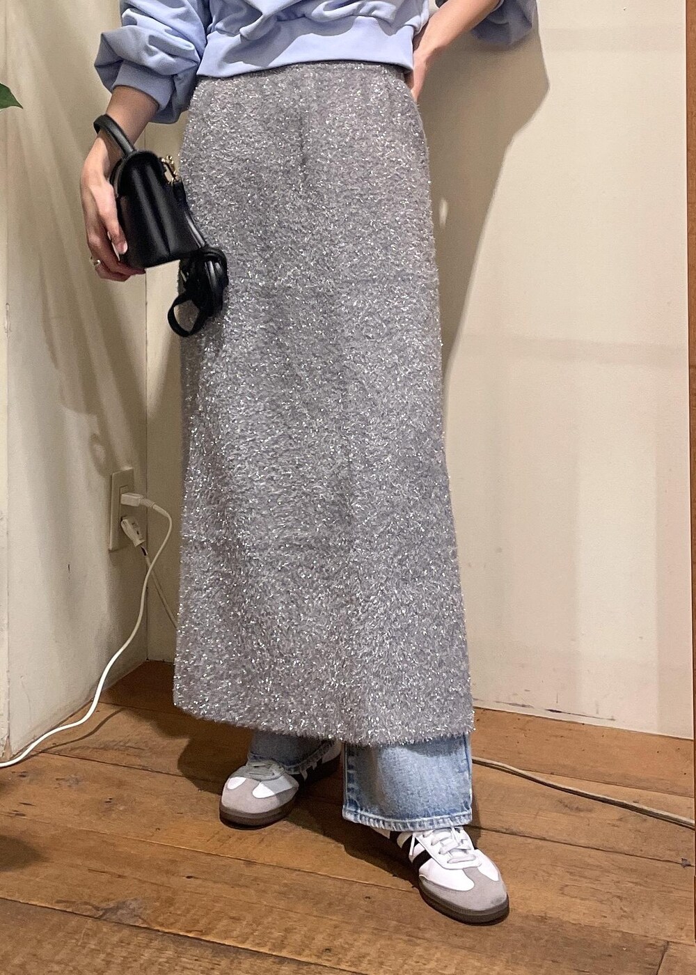 グレー系のスカート、ブルー系のデニムパンツ、ブラック系のショルダーバッグを着用したレディースの冬コーディネートの5枚目の写真
