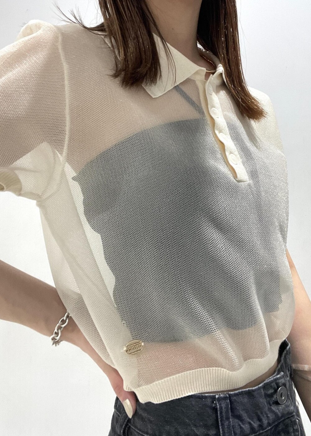 シルバー系のショルダーバッグ、ブラック系のデニムパンツ、ホワイト系のポロシャツを着用したレディースの夏コーディネートの6枚目の写真