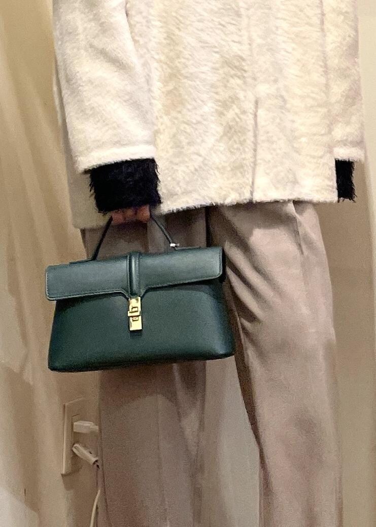 グリーン系のショルダーバッグ、ブラック系のブーツ、ブラック系のニット/セーターを着用したレディースの冬コーディネートの6枚目の写真