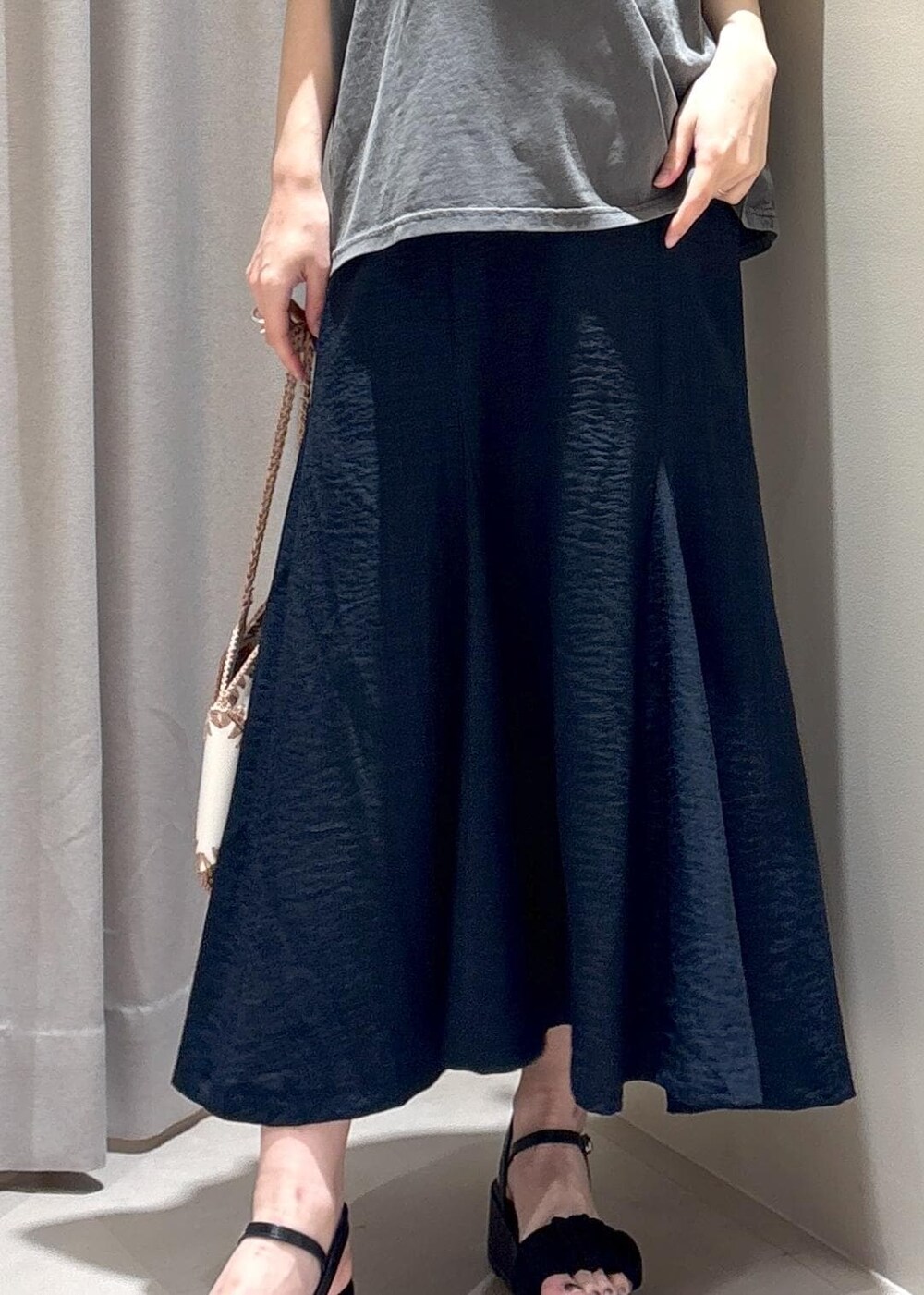 ホワイト系のハンドバッグ、ブルー系のスカート、グレー系のTシャツ/カットソーを着用したレディースの春コーディネートの6枚目の写真