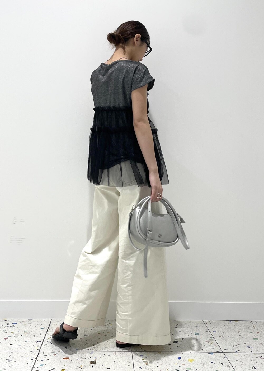 シルバー系のショルダーバッグ、ブラック系のサンダル、ブラック系のTシャツ/カットソーを着用したレディースの夏コーディネートの2枚目の写真