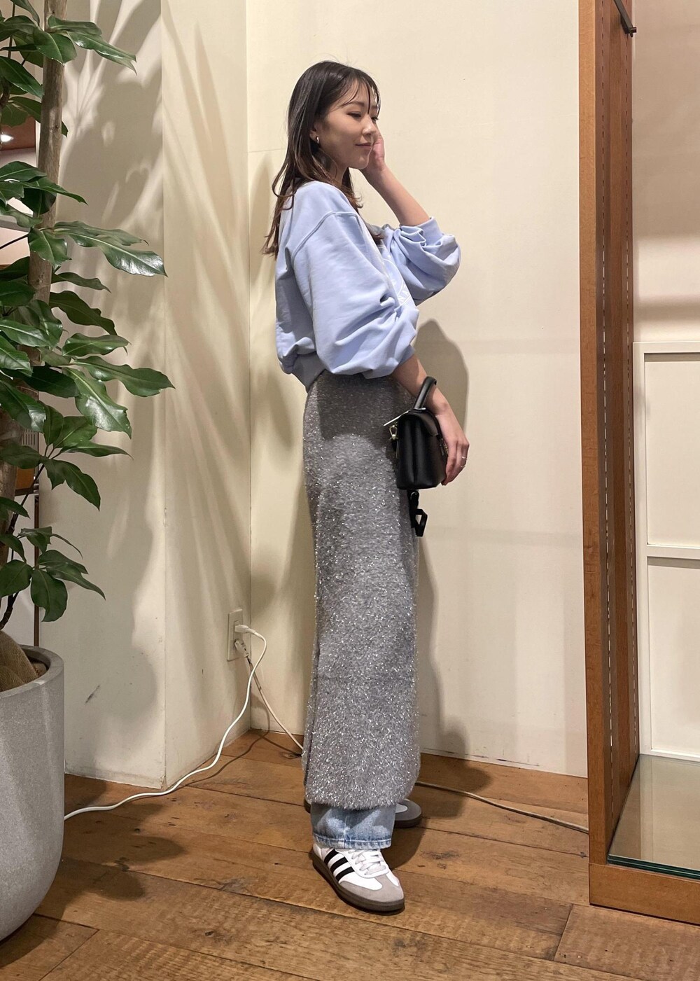 グレー系のスカート、ブルー系のデニムパンツ、ブラック系のショルダーバッグを着用したレディースの冬コーディネートの3枚目の写真
