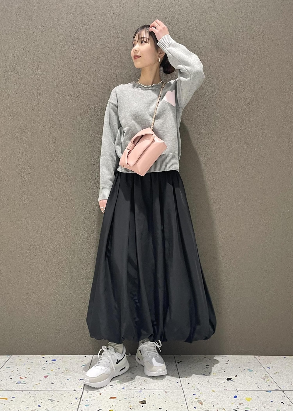 ブラック系のスカート、ピンク系のショルダーバッグ、グレー系のニット/セーターを着用したレディースの冬コーディネートの2枚目の写真