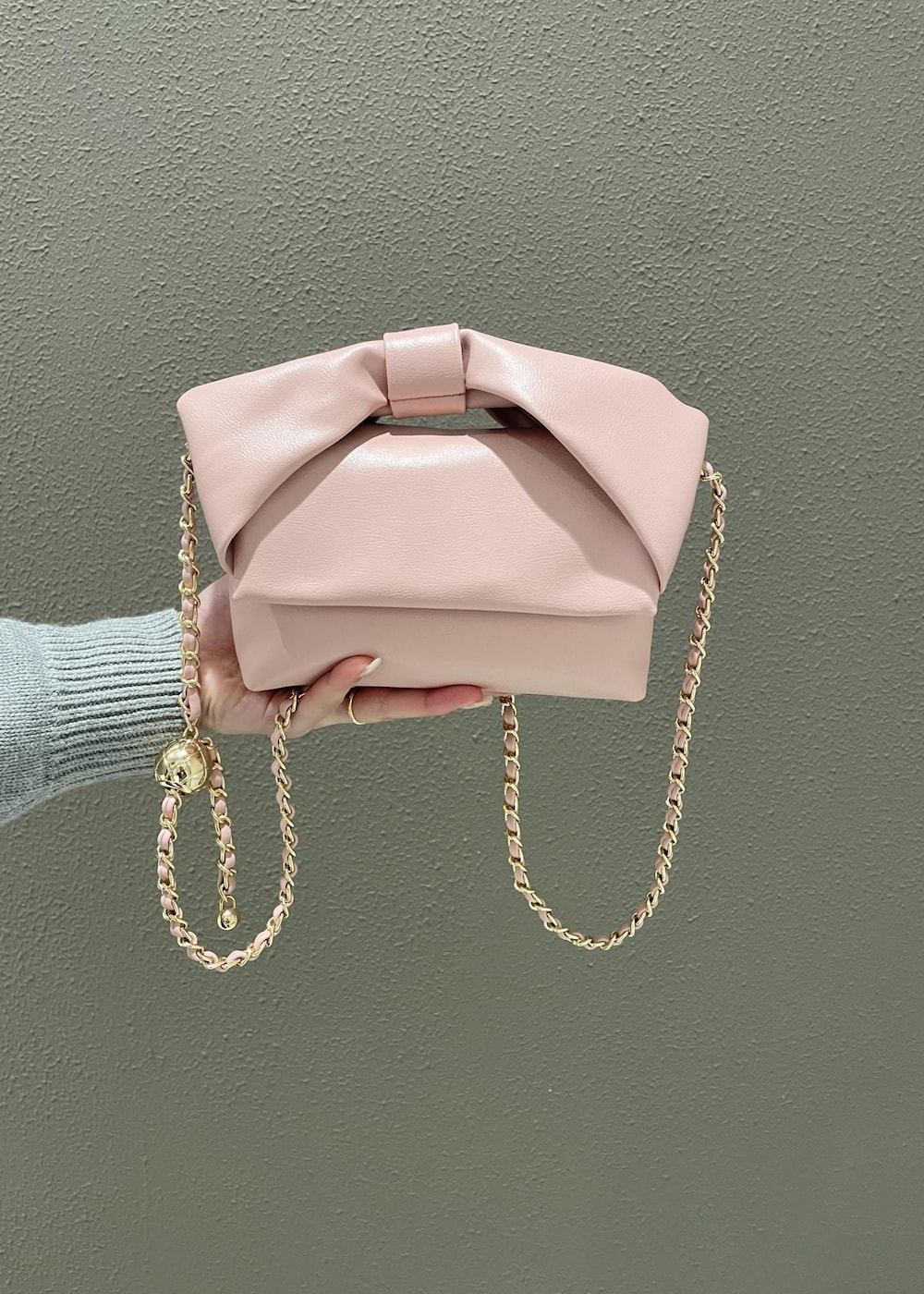 ブラック系のスカート、ピンク系のショルダーバッグ、グレー系のニット/セーターを着用したレディースの冬コーディネートの6枚目の写真