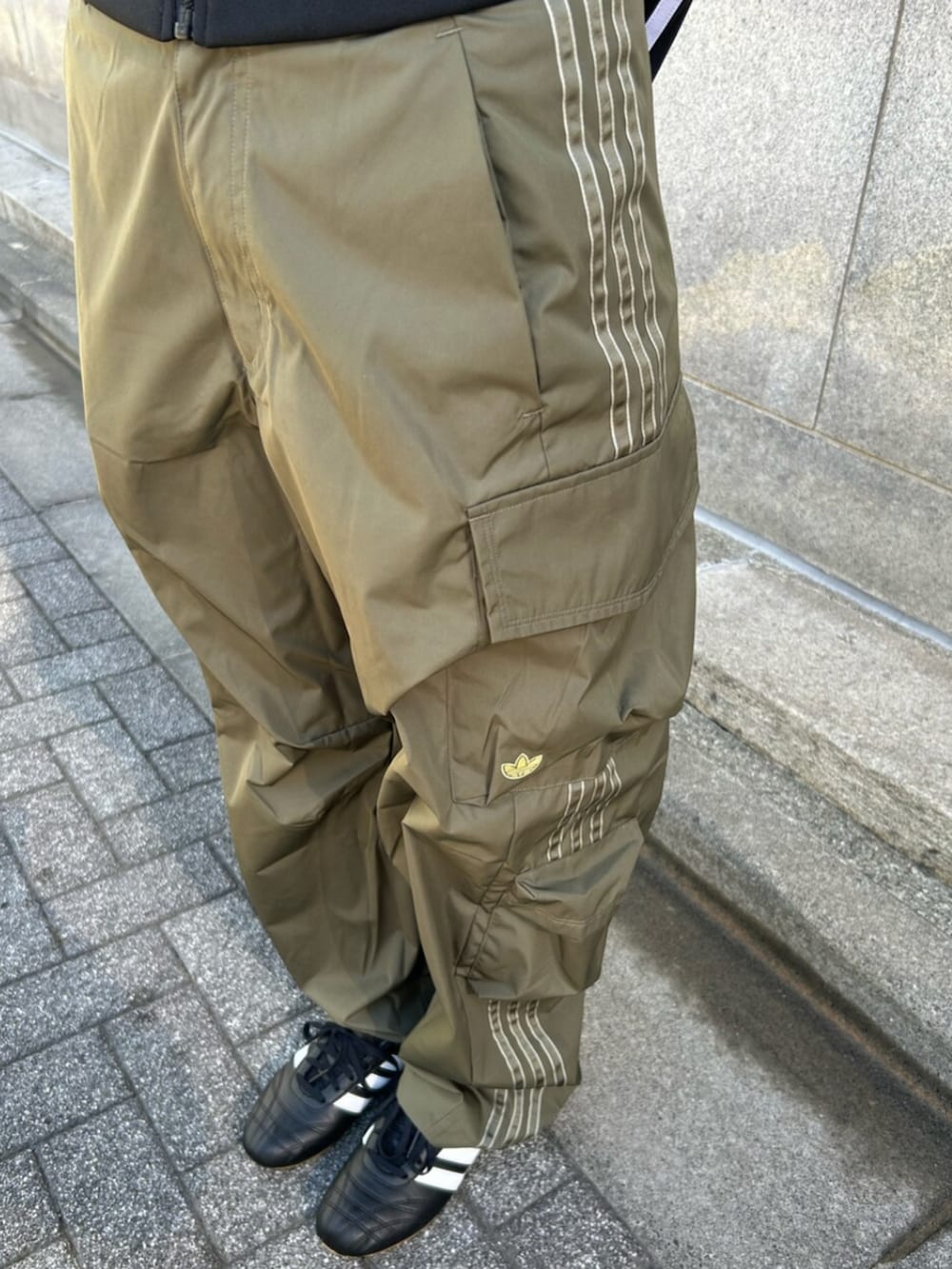 ブラック系のジャージ、グリーン系のカーゴパンツ、ブラック系のスニーカーを着用したレディースの春コーディネートの3枚目の写真