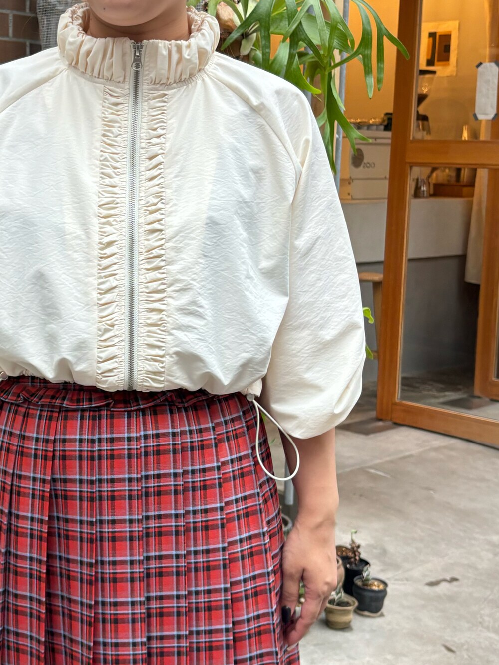 レッド系のスカート、ホワイト系のナイロンジャケット、ホワイト系のパンツを着用したレディースの秋コーディネートの3枚目の写真