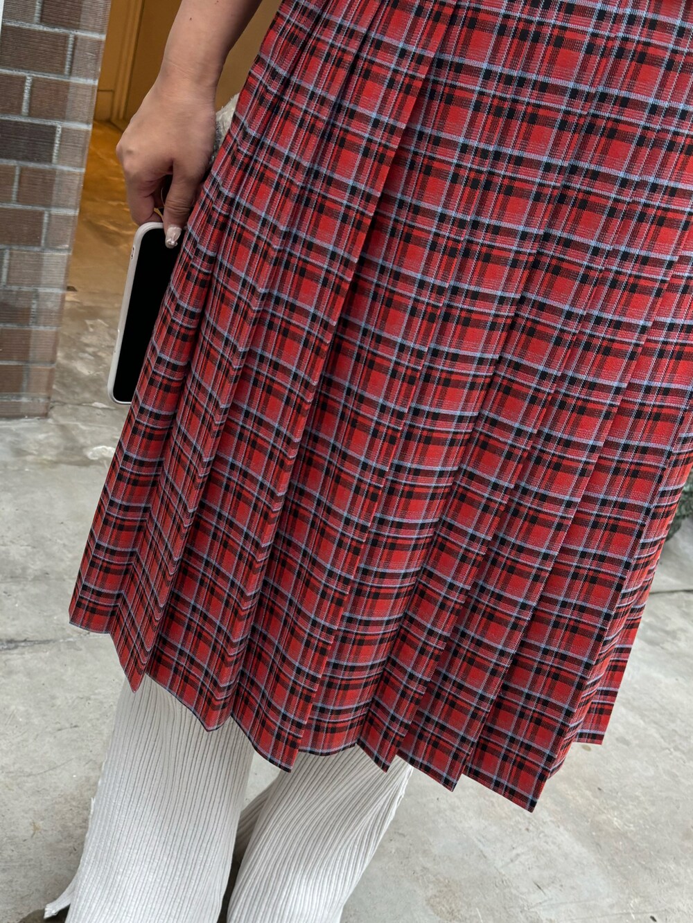 レッド系のスカート、ホワイト系のナイロンジャケット、ホワイト系のパンツを着用したレディースの秋コーディネートの2枚目の写真