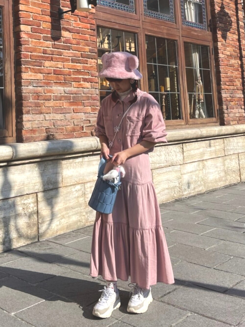 ピンク系のスカート、ピンク系のジャケット/アウター、ブルー系のハンドバッグを着用したレディースの秋コーディネートの2枚目の写真