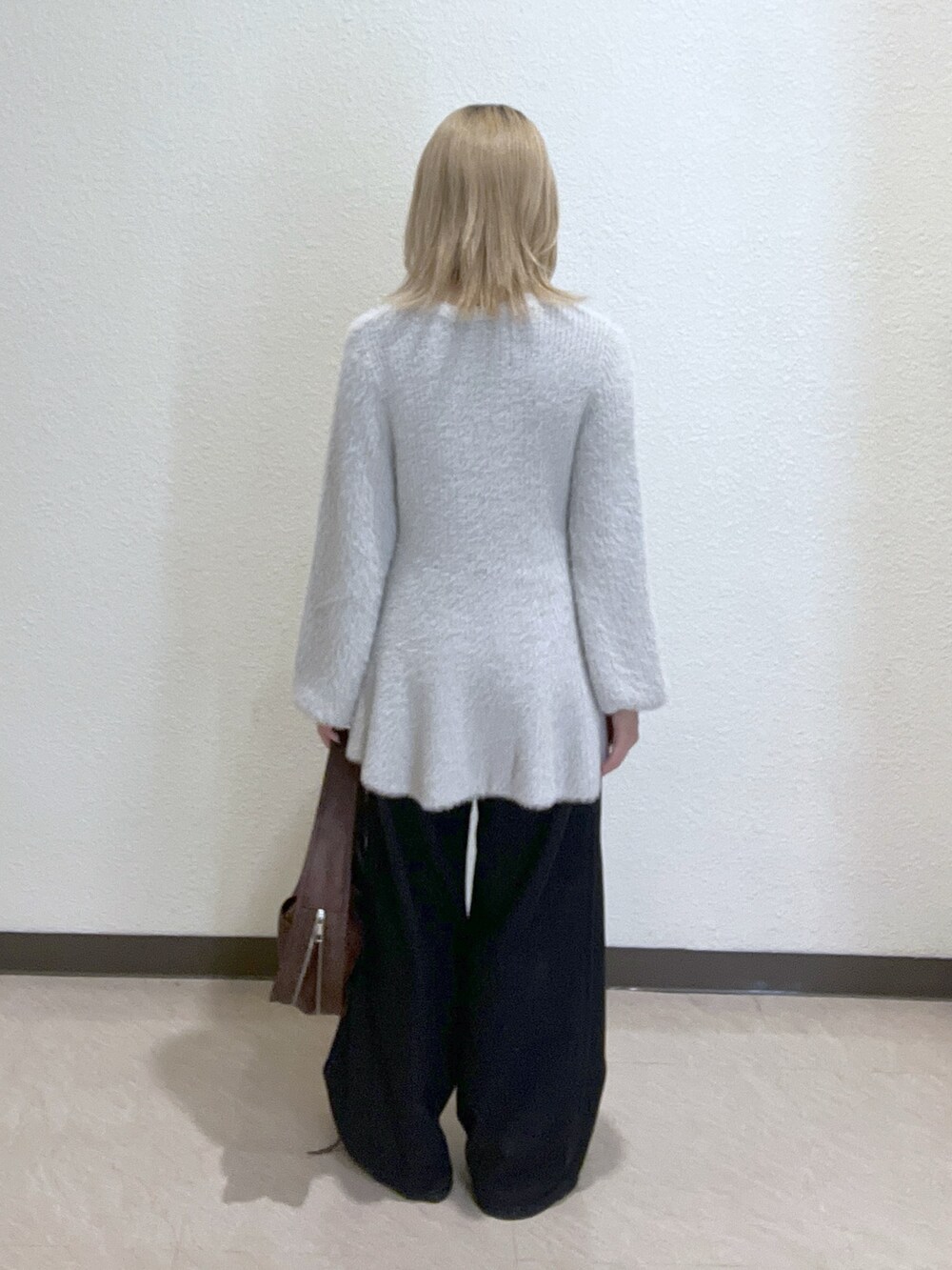 ブラウン系のハンドバッグ、グレー系のニット/セーター、ブラック系のデニムパンツを着用したレディースの秋コーディネートの3枚目の写真