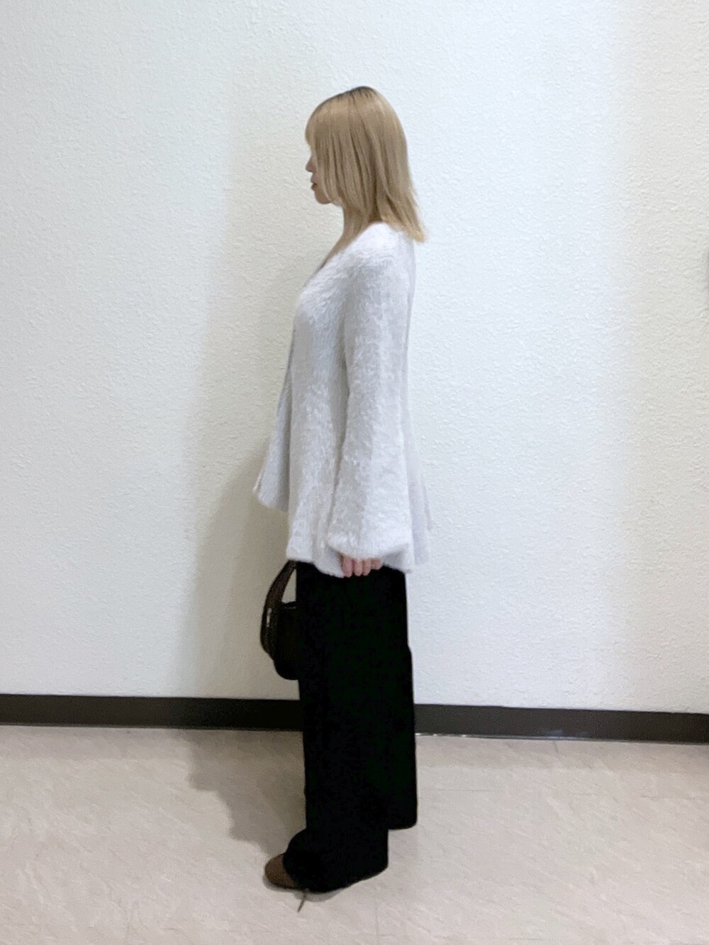 ブラウン系のハンドバッグ、グレー系のニット/セーター、ブラック系のデニムパンツを着用したレディースの秋コーディネートの2枚目の写真