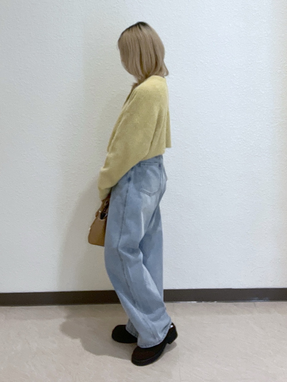 イエロー系のニット/セーター、ブルー系のデニムパンツ、ベージュ系のトートバッグを着用したレディースの秋コーディネートの2枚目の写真