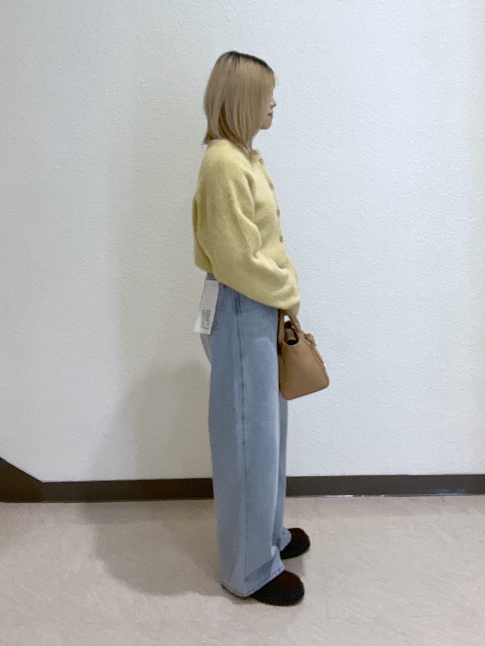 イエロー系のニット/セーター、ブルー系のデニムパンツ、ベージュ系のトートバッグを着用したレディースの秋コーディネートの4枚目の写真