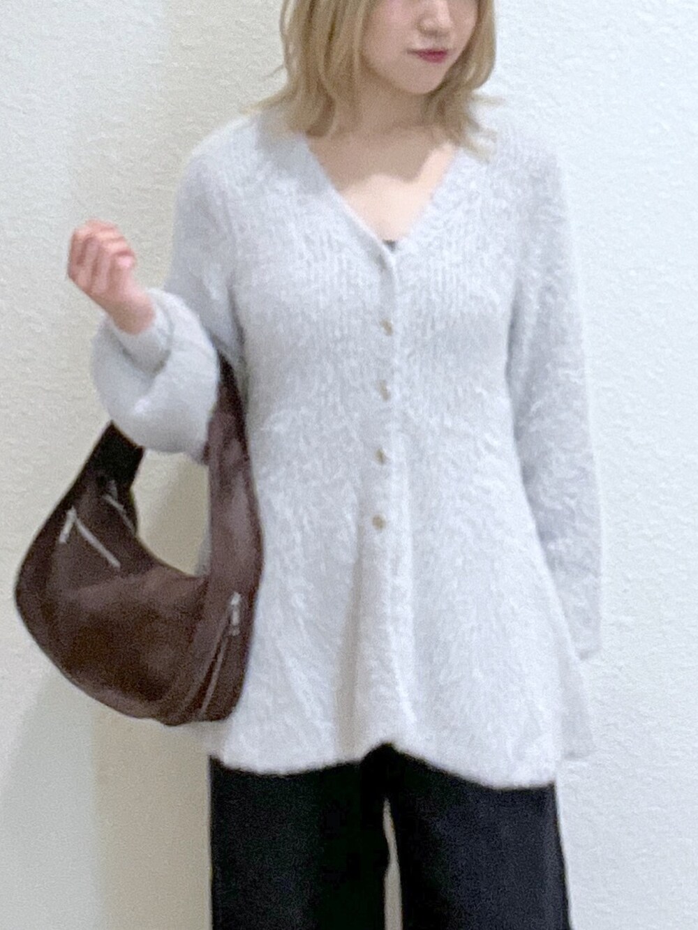 ブラウン系のハンドバッグ、グレー系のニット/セーター、ブラック系のデニムパンツを着用したレディースの秋コーディネートの5枚目の写真