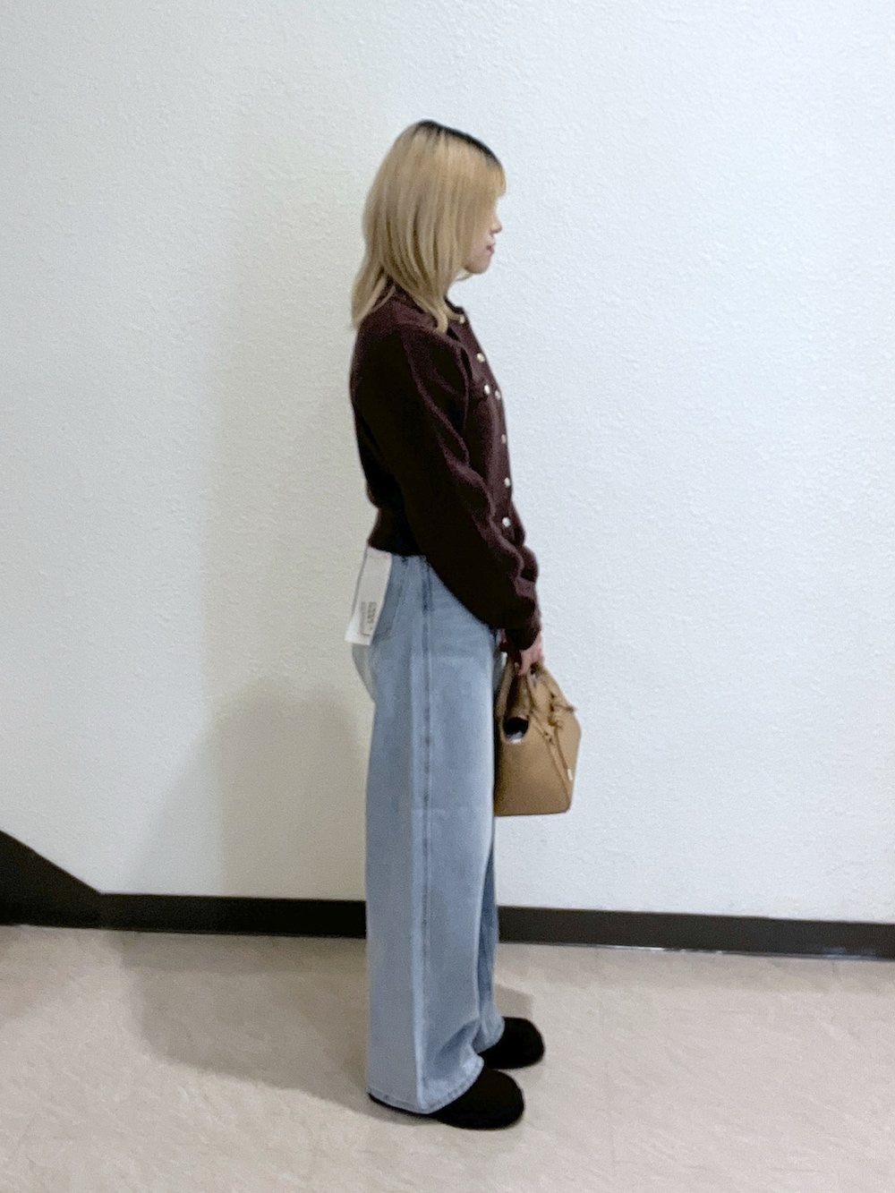 ブラウン系のニット/セーター、ベージュ系のトートバッグ、ブルー系のデニムパンツを着用したレディースの秋コーディネートの2枚目の写真