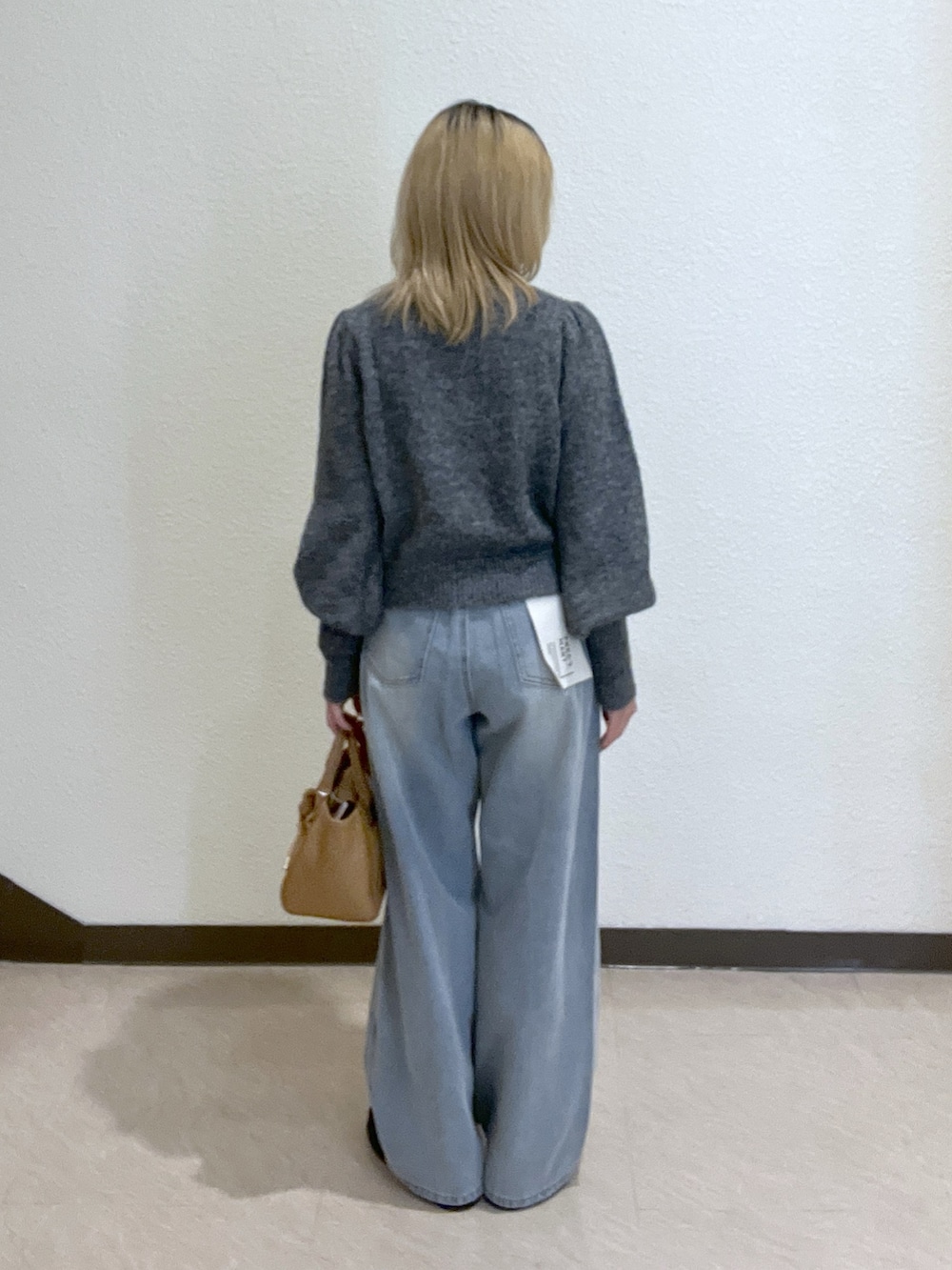 グレー系のニット/セーター、ブルー系のデニムパンツ、ベージュ系のトートバッグを着用したレディースの秋コーディネートの3枚目の写真