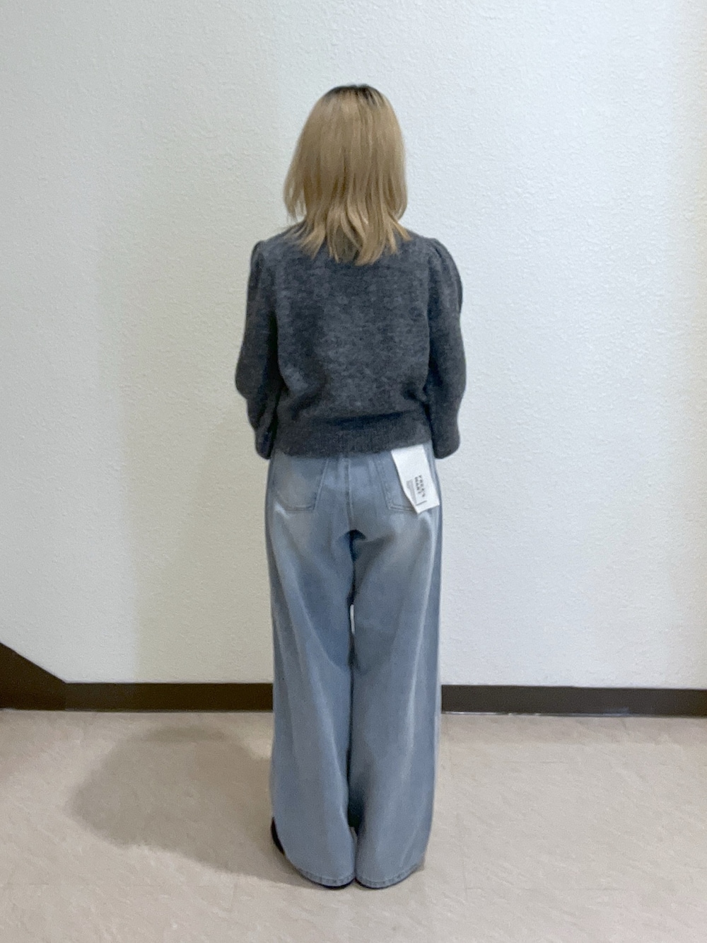 グレー系のニット/セーター、ブルー系のデニムパンツ、ベージュ系のトートバッグを着用したレディースの秋コーディネートの4枚目の写真