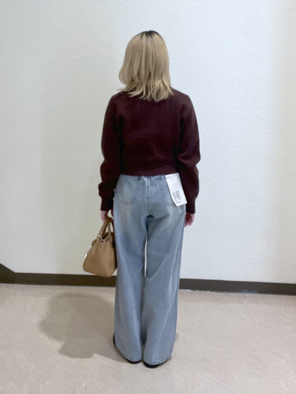 ブラウン系のニット/セーター、ベージュ系のトートバッグ、ブルー系のデニムパンツを着用したレディースの秋コーディネートの4枚目の写真