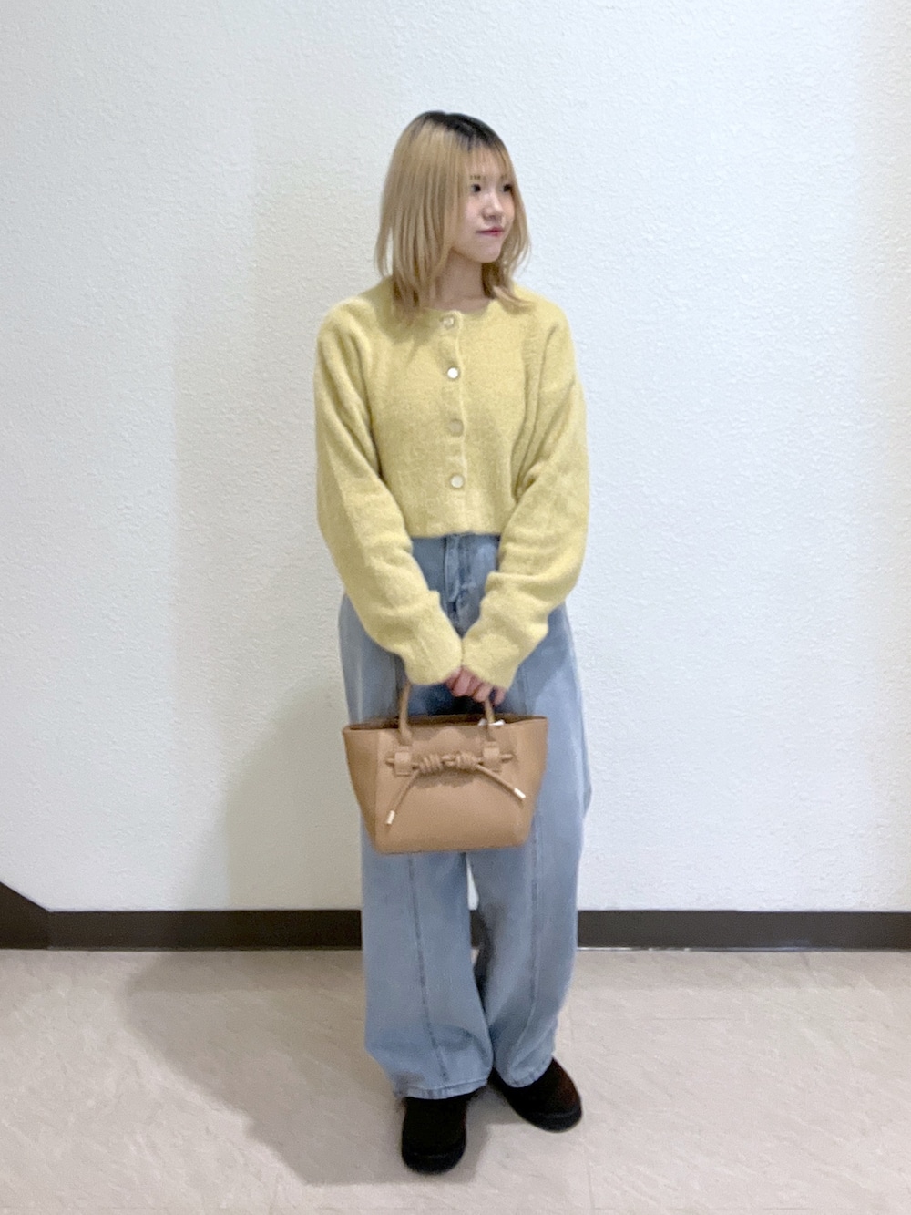 イエロー系のニット/セーター、ブルー系のデニムパンツ、ベージュ系のトートバッグを着用したレディースの秋コーディネートの5枚目の写真