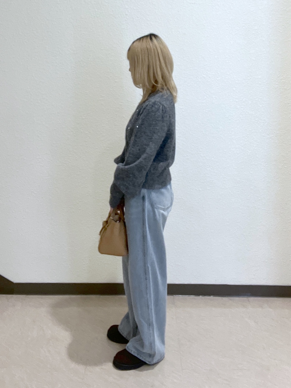 グレー系のニット/セーター、ブルー系のデニムパンツ、ベージュ系のトートバッグを着用したレディースの秋コーディネートの5枚目の写真