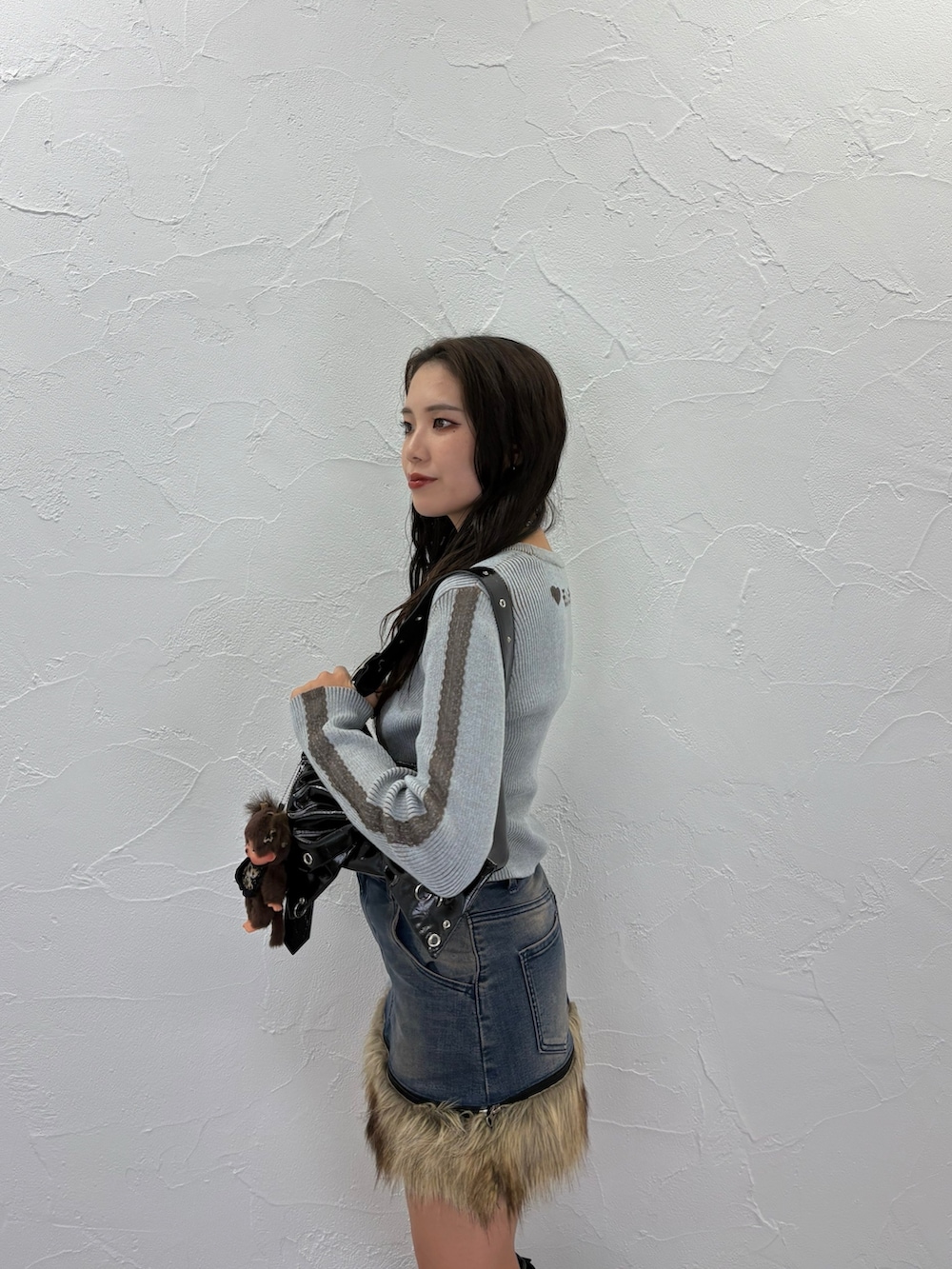 ブルー系のニット/セーター、ブラック系のショルダーバッグ、ブルー系のスカートを着用したレディースの夏コーディネートの4枚目の写真