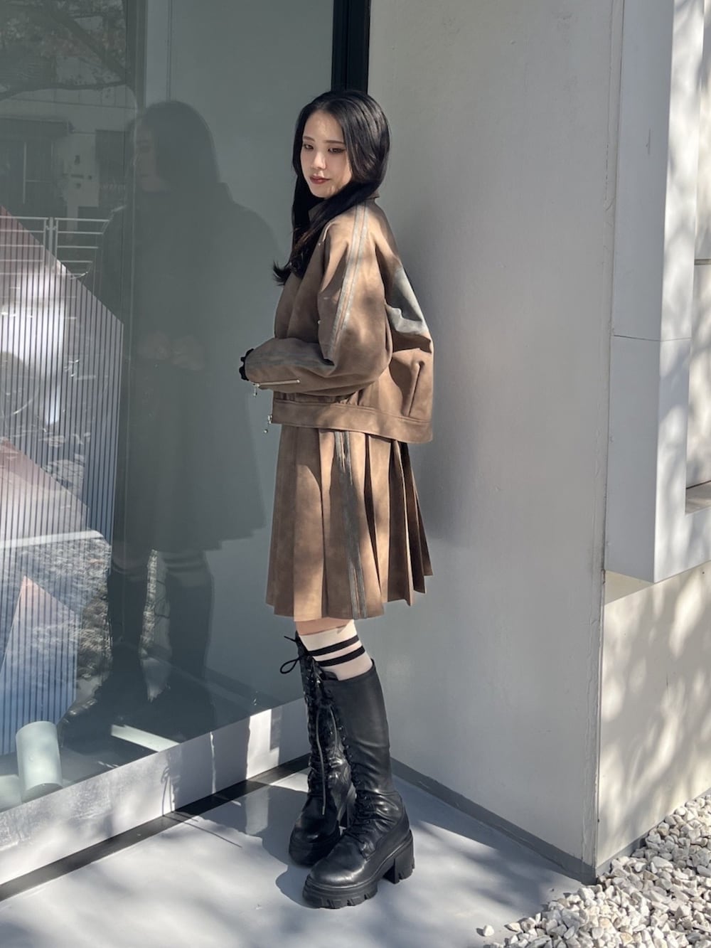 ブラウン系のスカート、ブラウン系のブルゾン、ブラック系のTシャツ/カットソーを着用したレディースの冬コーディネートの2枚目の写真