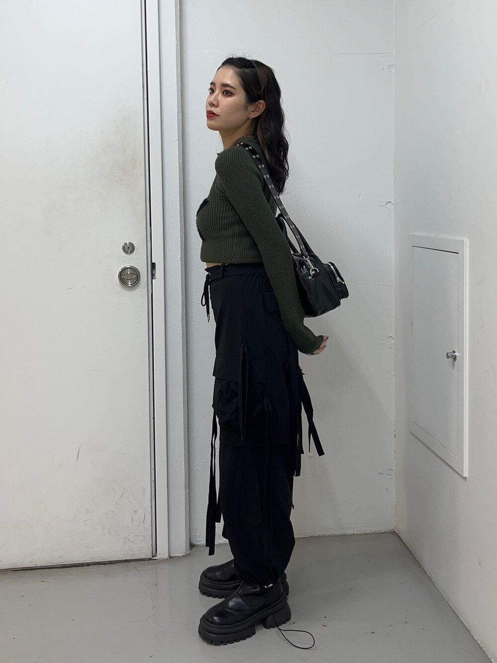 グリーン系のニット/セーター、ブラック系のその他パンツ、ブラック系のボストンバッグを着用したレディースの冬コーディネートの2枚目の写真