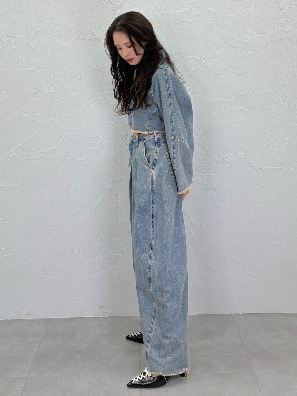 ブルー系のデニムジャケット、ブルー系のデニムパンツ、ブラック系のパンプスを着用したレディースの秋コーディネートの3枚目の写真