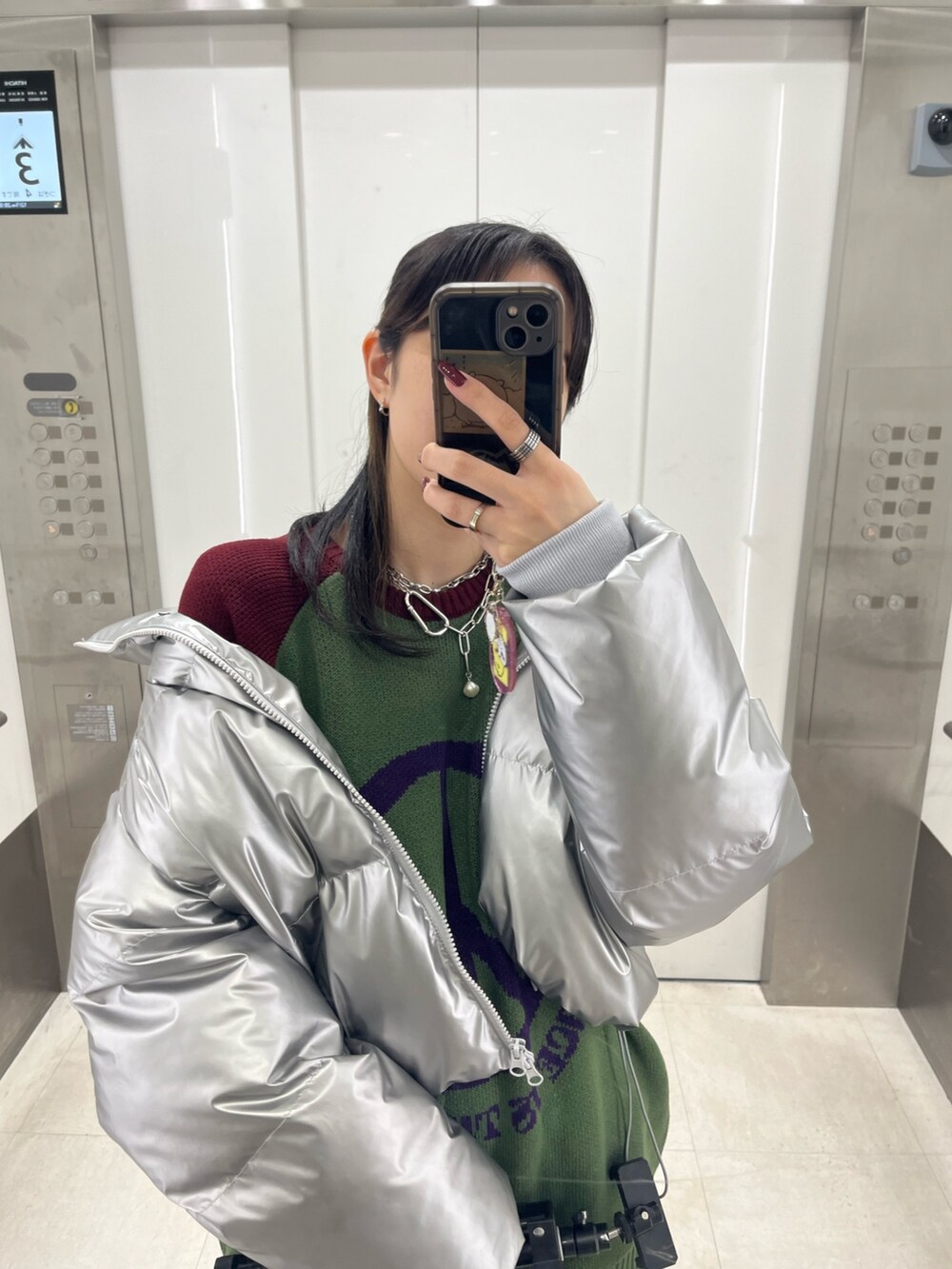 シルバー系のダウンジャケット/コート、グリーン系のニット/セーター、ブラック系のその他パンツを着用したレディースの冬コーディネートの5枚目の写真