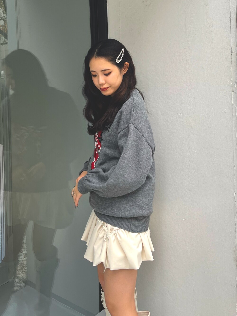 グレー系のニット/セーター、ホワイト系のスカート、ホワイト系のブーツを着用したレディースの冬コーディネートの4枚目の写真