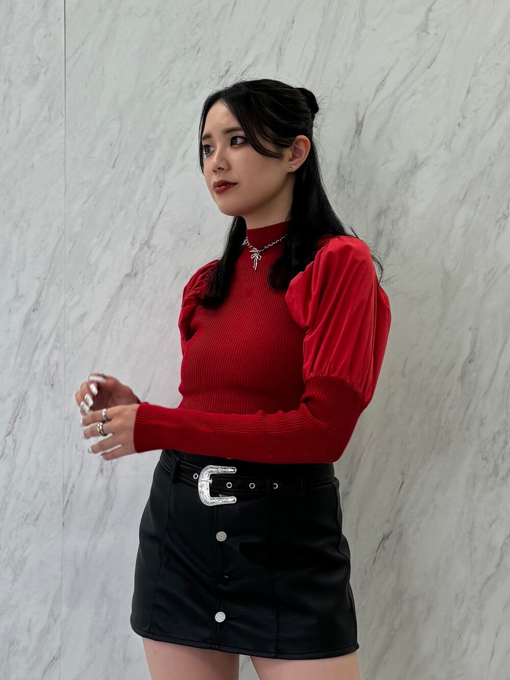 レッド系のニット/セーター、ブラック系のスカート、ブラック系のブーツを着用したレディースの夏コーディネートの6枚目の写真