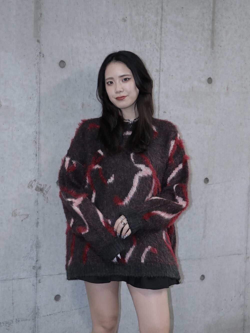 ブラック系のニット/セーター、ブラック系のスカート、ブラック系のブーツを着用したレディースの秋コーディネートの4枚目の写真