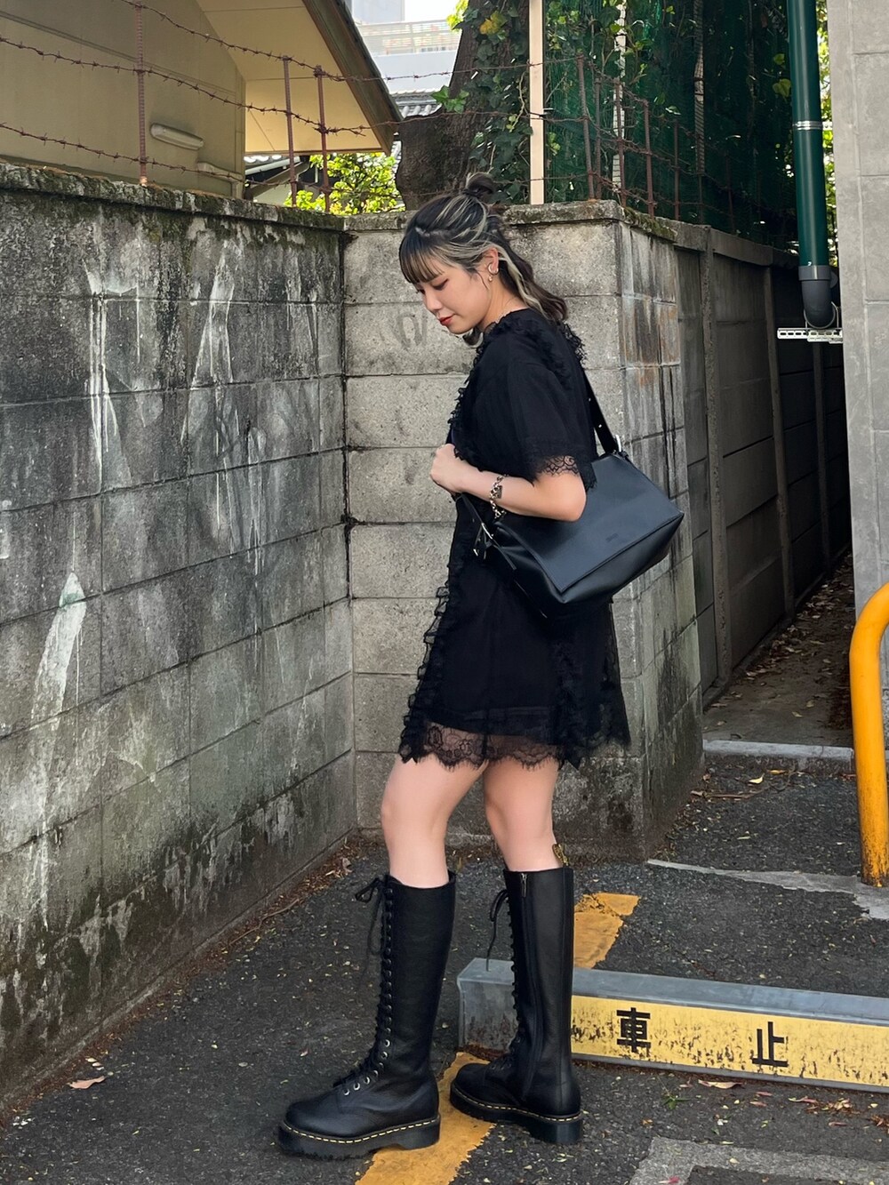 ブラック系のワンピース、ブラック系のメッセンジャーバッグ、ブラック系のブーツを着用したレディースの春コーディネートの3枚目の写真