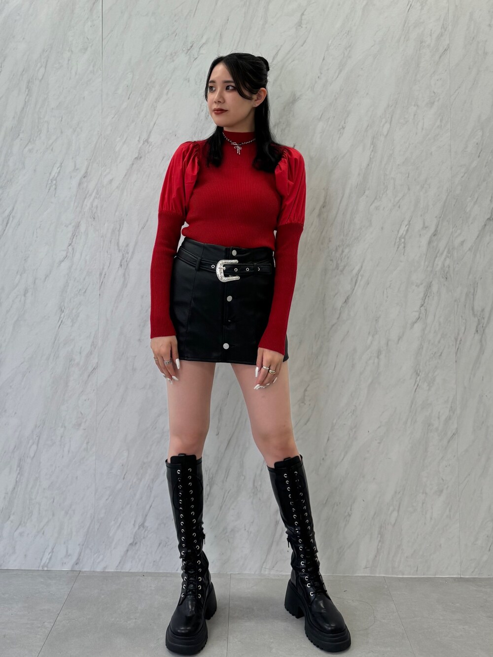 レッド系のニット/セーター、ブラック系のスカート、ブラック系のブーツを着用したレディースの夏コーディネートの2枚目の写真