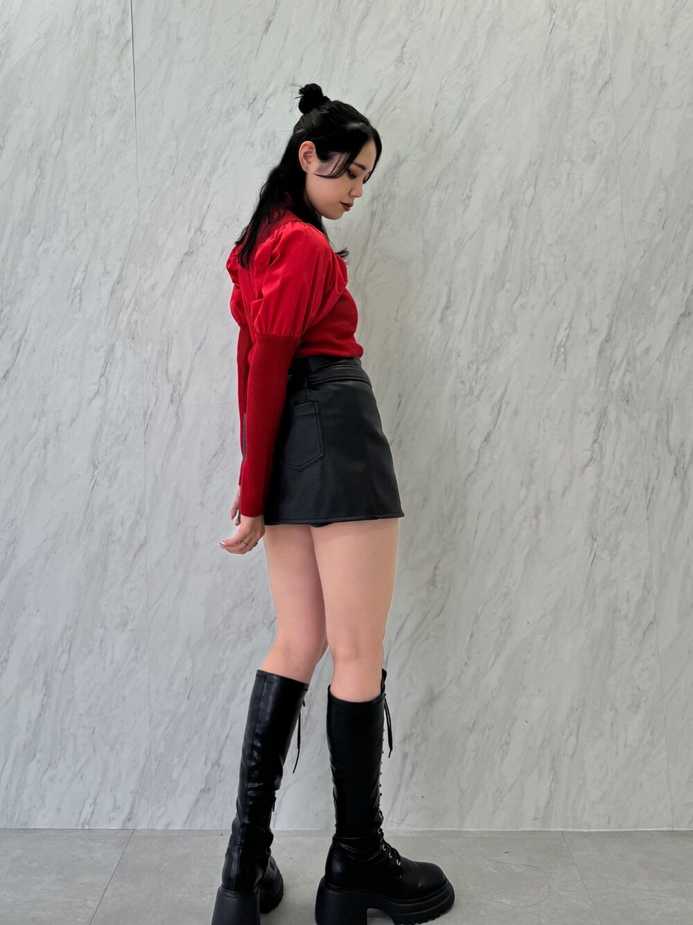 レッド系のニット/セーター、ブラック系のスカート、ブラック系のブーツを着用したレディースの夏コーディネートの3枚目の写真