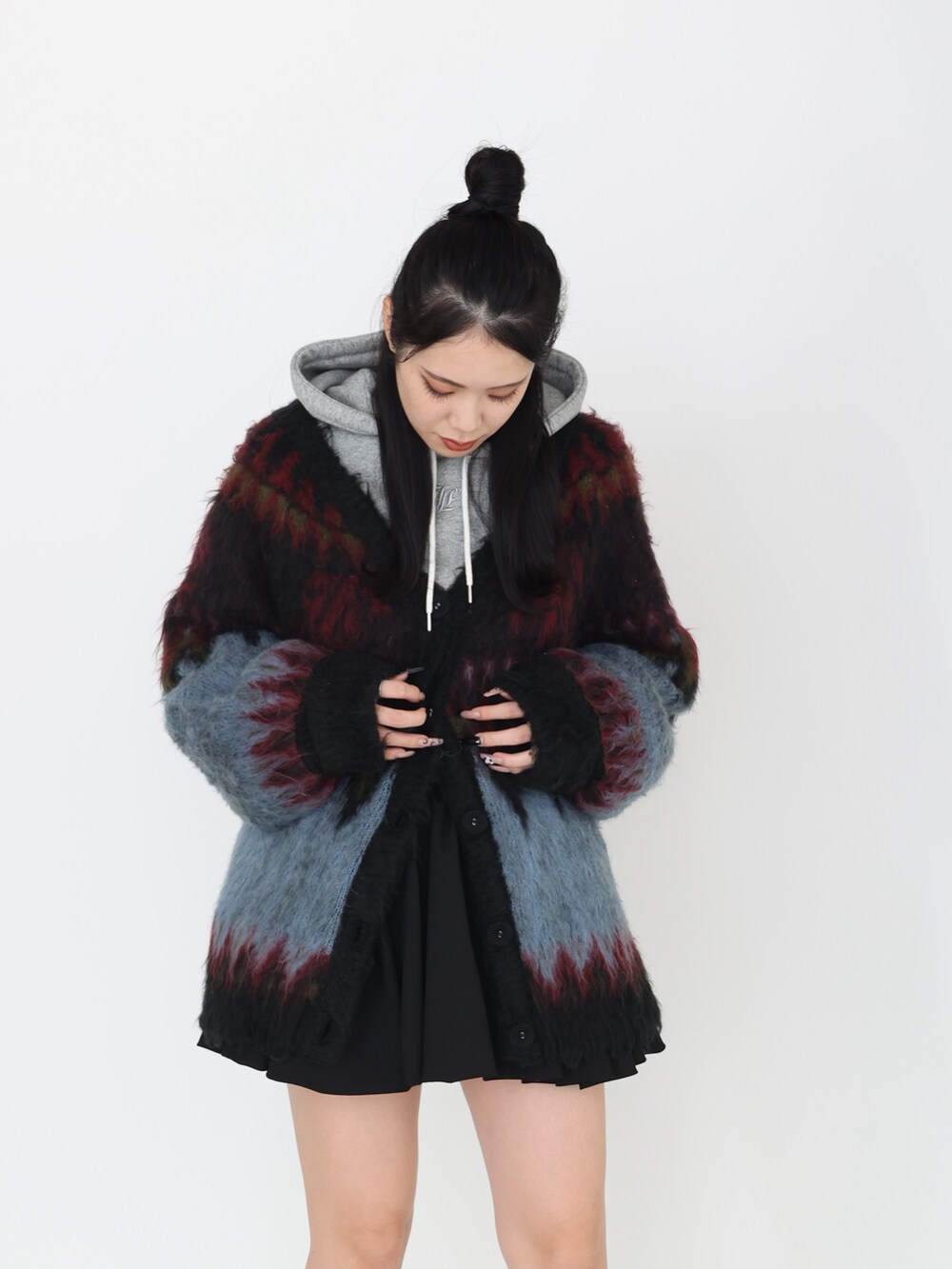 ブラック系のカーディガン/ボレロ、グレー系のパーカー、ブラック系のスカートを着用したレディースの秋コーディネートの3枚目の写真