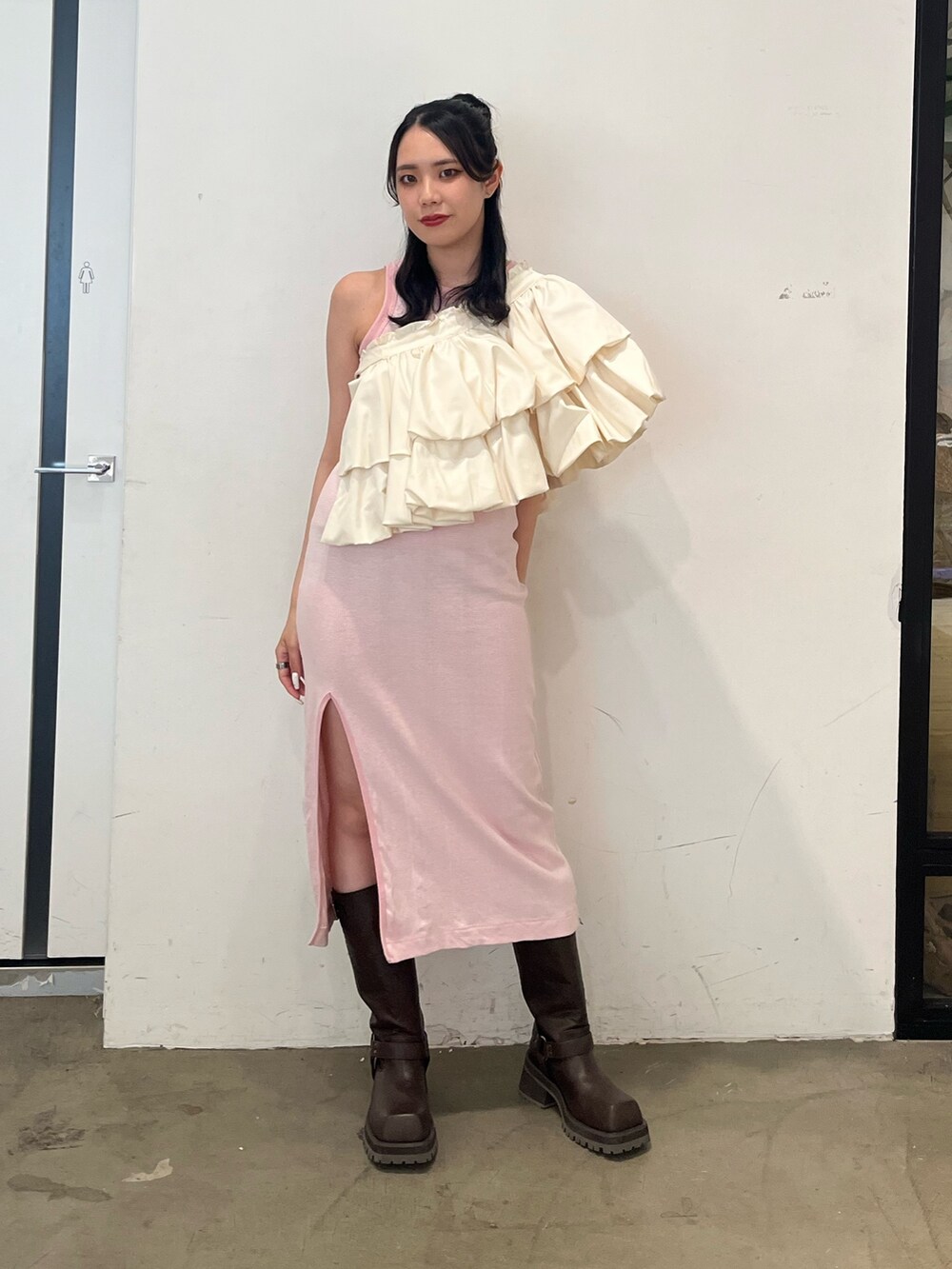 ピンク系のワンピース、ホワイト系のスカート、ブラウン系のブーツを着用したレディースの春コーディネートの2枚目の写真