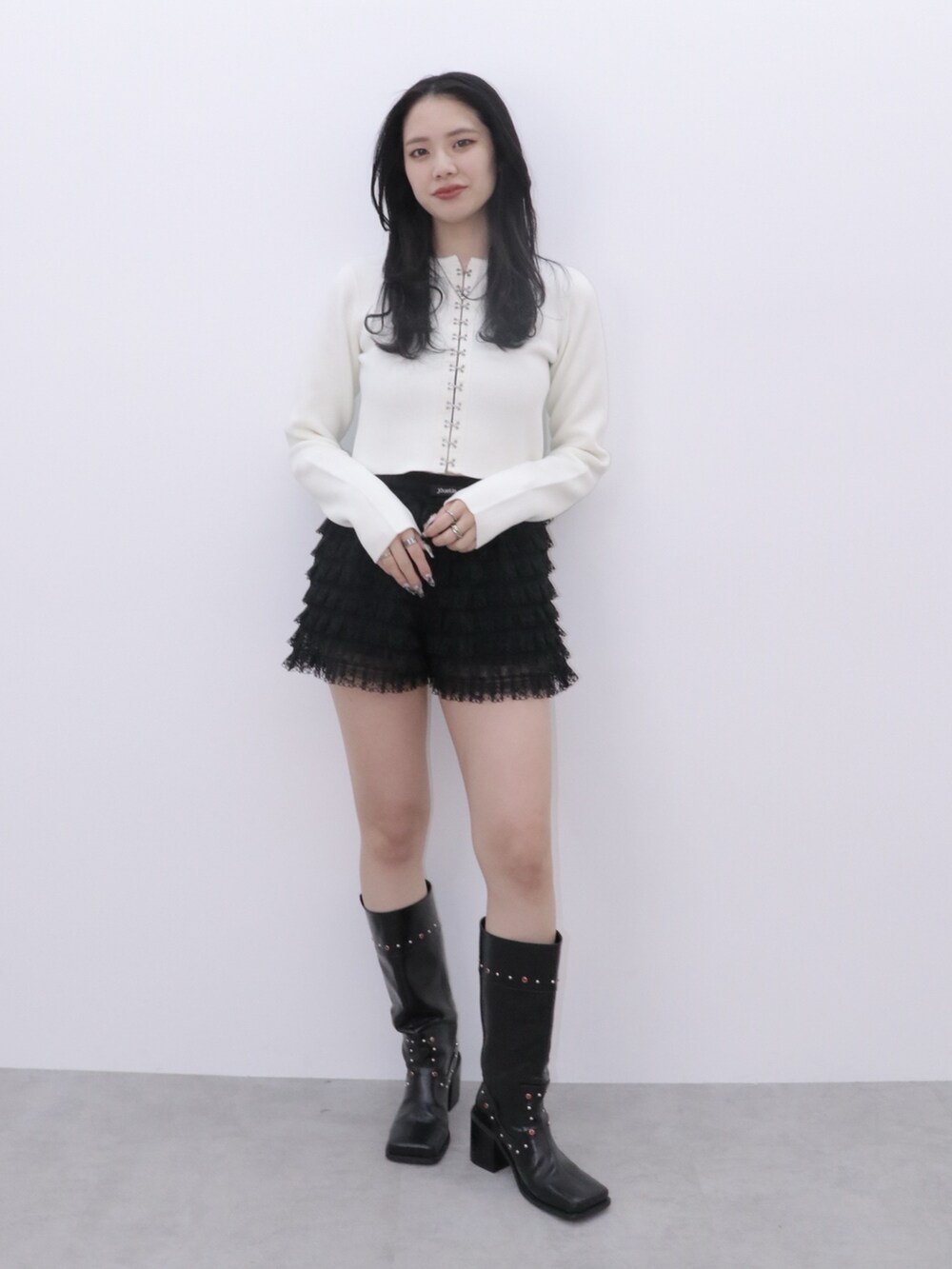 ブラック系のその他パンツ、ホワイト系のカーディガン/ボレロ、ブラック系のブーツを着用したレディースの冬コーディネートの2枚目の写真