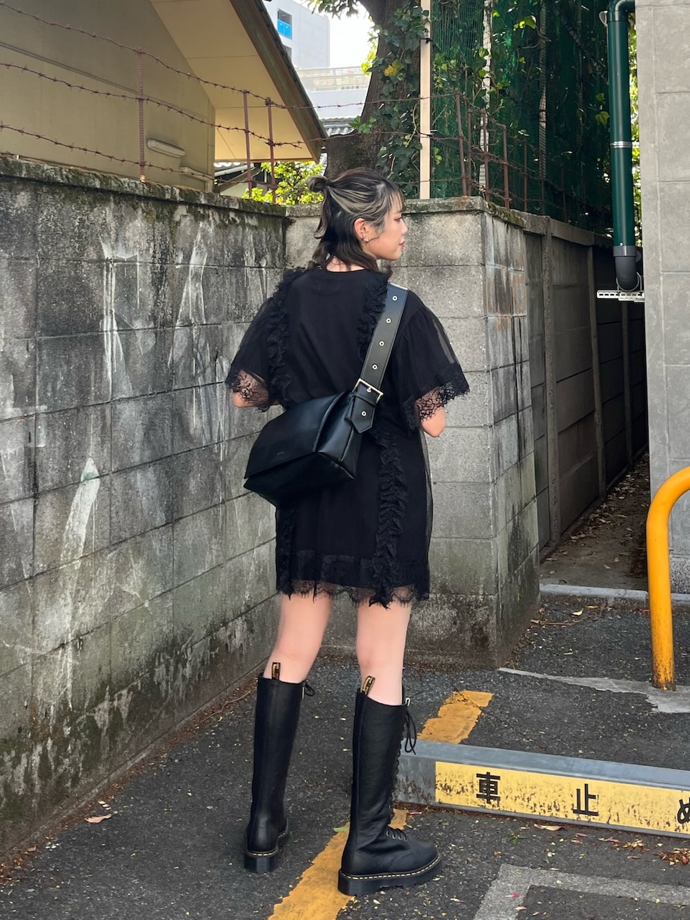 ブラック系のワンピース、ブラック系のメッセンジャーバッグ、ブラック系のブーツを着用したレディースの春コーディネートの2枚目の写真