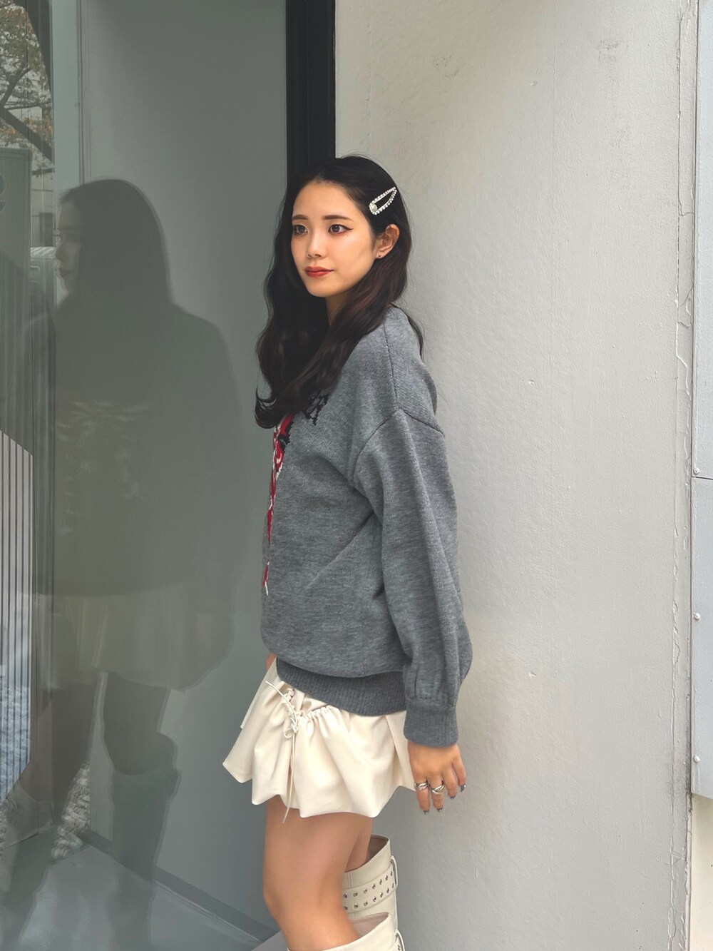 グレー系のニット/セーター、ホワイト系のスカート、ホワイト系のブーツを着用したレディースの冬コーディネートの5枚目の写真