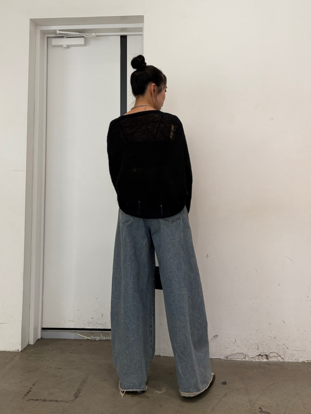 ブラック系のニット/セーター、ブルー系のデニムパンツ、ブラック系のハンドバッグを着用したレディースの秋コーディネートの3枚目の写真