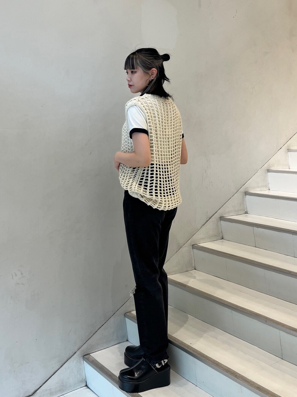 ブラック系のデニムパンツ、ホワイト系のTシャツ/カットソー、ホワイト系のベストを着用したレディースの春コーディネートの2枚目の写真