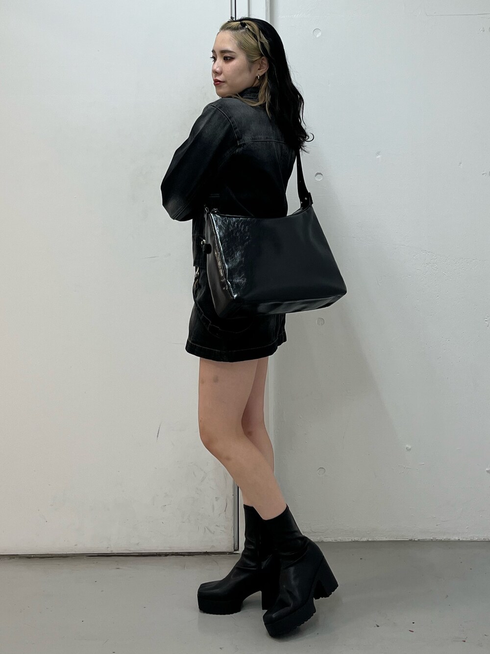 ブラック系のデニムジャケット、ブラック系のショルダーバッグ、ブラック系のブーツを着用したレディースの冬コーディネートの2枚目の写真