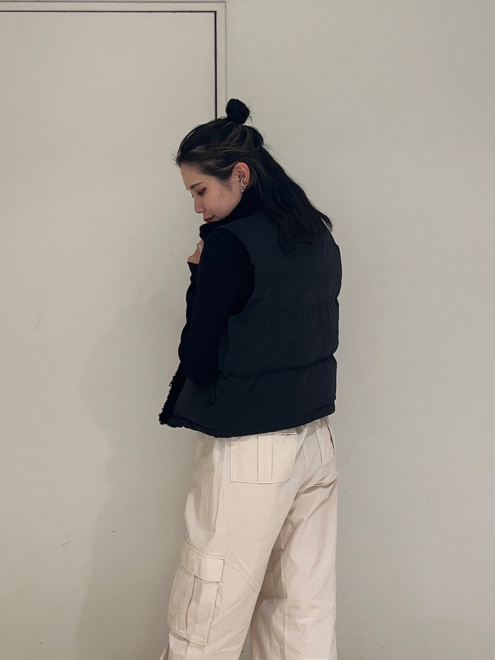 ブラック系のダウンベスト、ホワイト系のカーゴパンツ、ブラック系のTシャツ/カットソーを着用したレディースの秋コーディネートの4枚目の写真