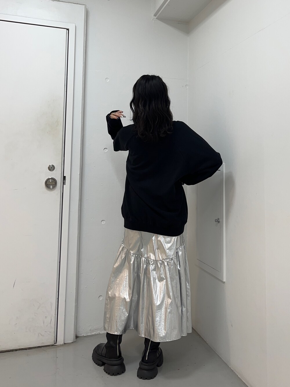 ブラック系のスウェット、シルバー系のスカート、ブラック系のブーツを着用したレディースの冬コーディネートの2枚目の写真