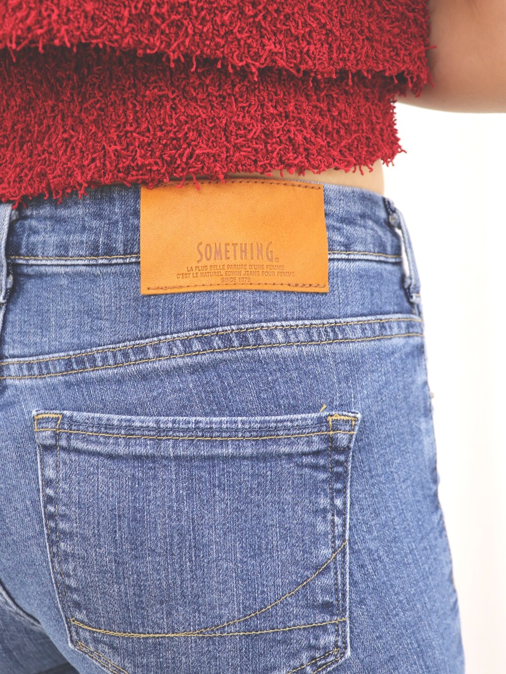 ブルー系のデニムパンツ、レッド系のアンサンブル、ブラック系のパンプスを着用したレディースの夏コーディネートの5枚目の写真