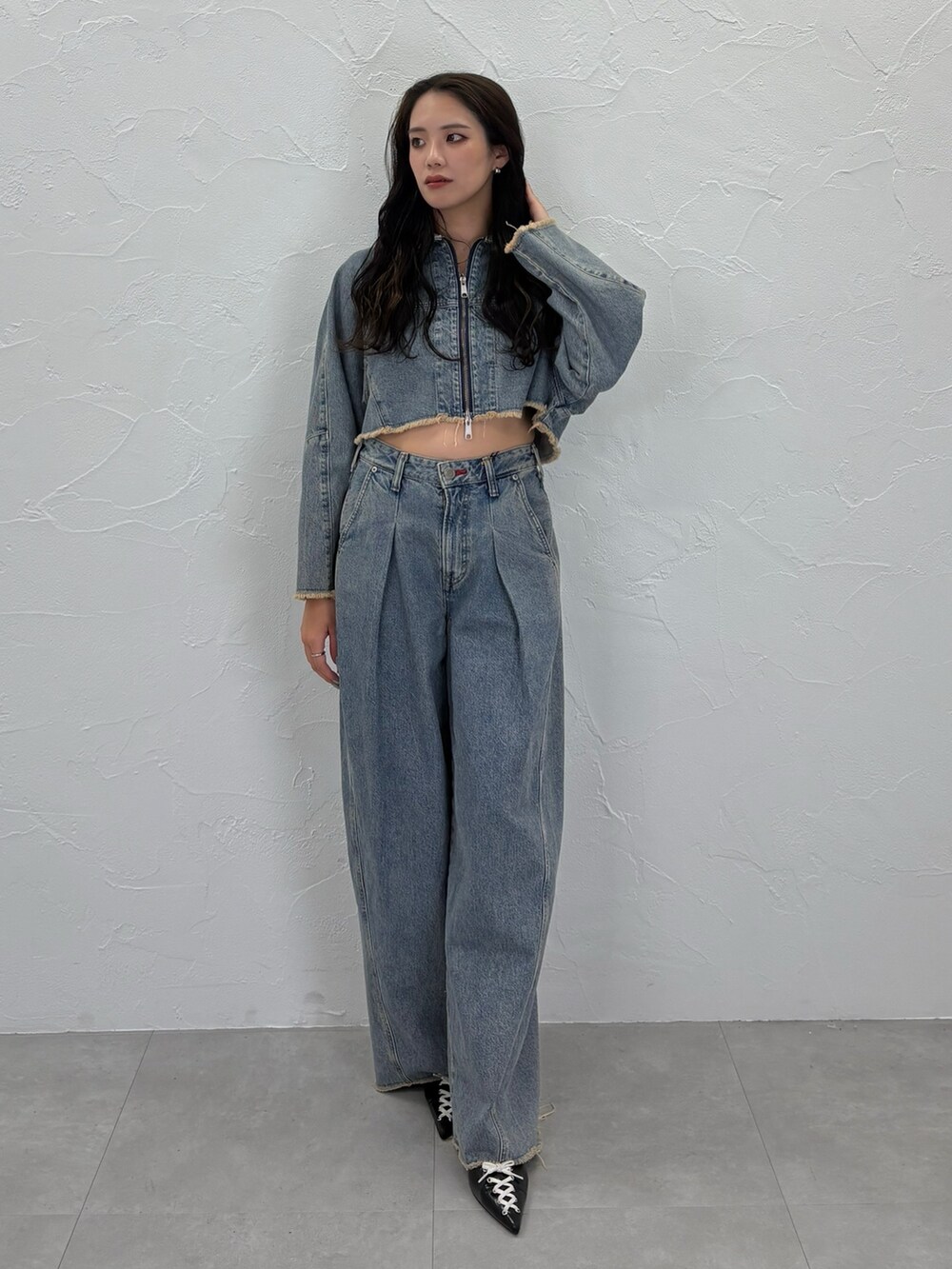 ブルー系のデニムジャケット、ブルー系のデニムパンツ、ブラック系のパンプスを着用したレディースの秋コーディネートの2枚目の写真